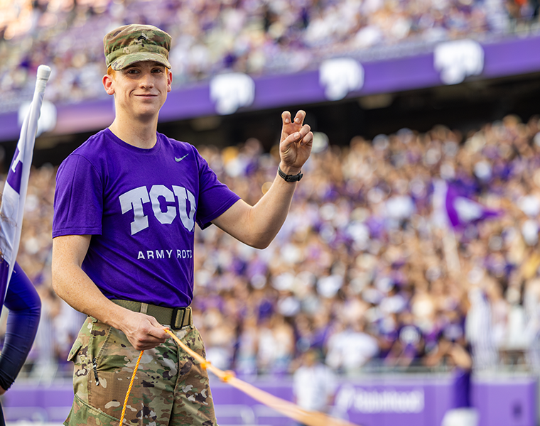 TCU ROTC student at a football game throwing up the go frogs hand sign