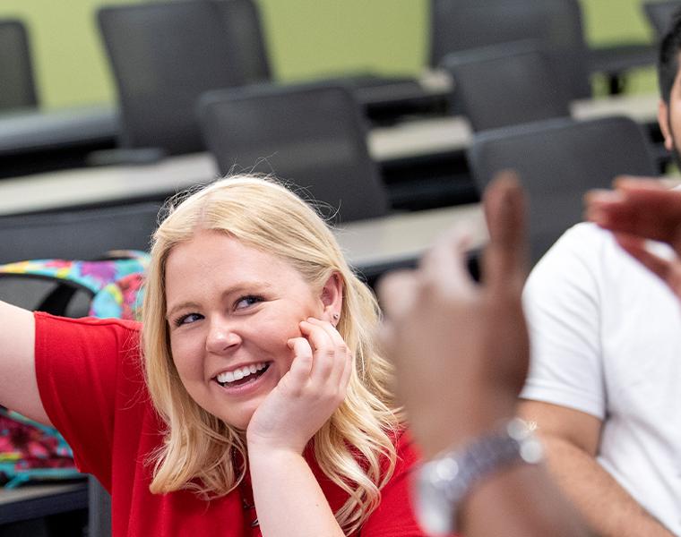 female student smiling while raising hand