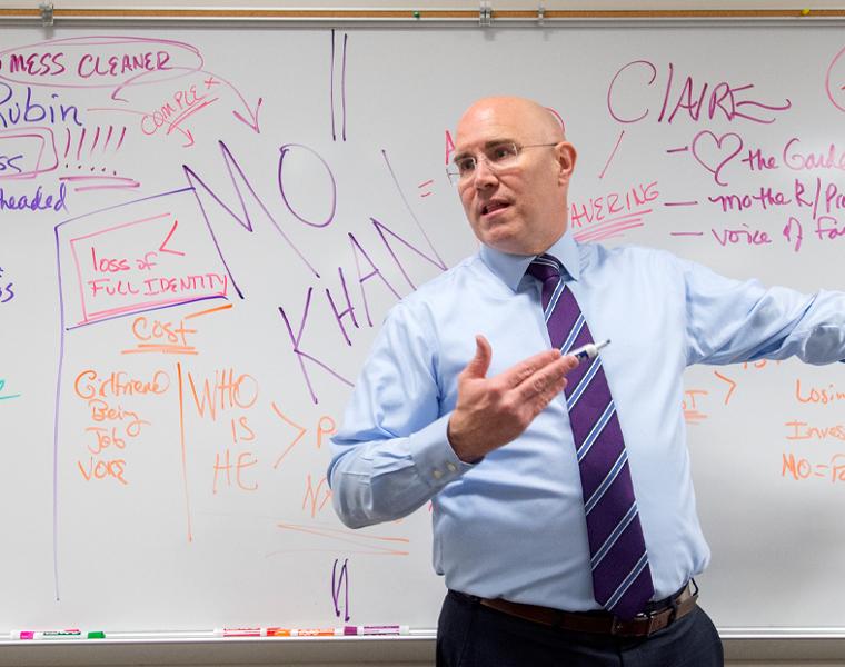 Professor making notes on a dry erase board